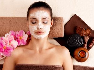 Young woman relaxing with cosmetic mask on face at beauty salon- indoors